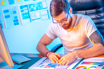 Poster - male graphic designer at the desk. design for mobile devices. a man selects a color for a mobile app