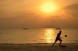 Man playing beach football at sunset