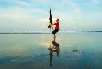 healthy and attractive fit couple of acrobats  doing acroyoga balance and meditation exercise on beautiful desert beach practicing balance and harmony posing