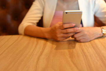 image selective focus on wooden table work of office with business woman using mobile phone technology