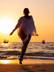 young woman walking in the sea at sunset