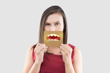 Asian Woman In The Red Shirt Holding A Brown Paper With The Yellow Teeth Cartoon Picture Of His Mouth Against The Gray Background, Bad Breath Or Halitosis, The Concept With Healthcare Gums And Teeth