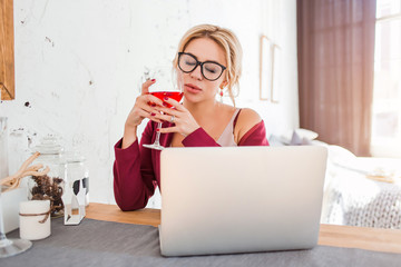 Poster - Young female entrepreneur sitting at table in her home office working on laptop