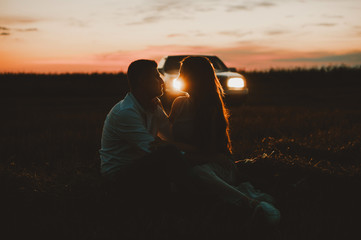 Sunset, driving day, a couple sitting in filed on sunset and car light