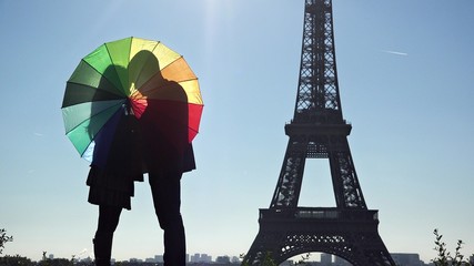 Couple of lovers silhouettes with colored umbrella close to Eiffel tower in Paris