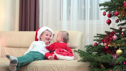 Wall Mural - Happy brothers embrace smiling laughing close Christmas tree, Santa costume, fell the real joy of celebration close family