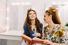 Two Attractive Joyful Models With Stylish Makeups, Luxury Coiffures Having Fun, Drinking Champagne In Haidresser Salon. Friends Together, Expressing True Positive Emotions, Preparation To Party