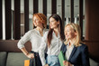 © alfa27 - Group of three successful positive female entrepreneurs dressed in formal wear standing and smiling at camera after meeting, small business concept