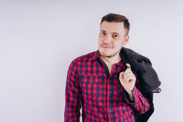 Wall Mural - Cool man with jacket on shoulder Portrait of young handsome male in red plaid shirt holding leather jacket on shoulder against white background