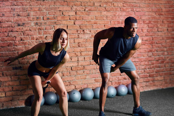 Wall Mural - Young caucasian woman athlete working out with kettlebells with the help of personal trainer during body core cross fit workout