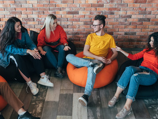 Casual business meeting. Creative millennials team relaxing in lounge area. Man women talking, sharing ideas. Leisure time.