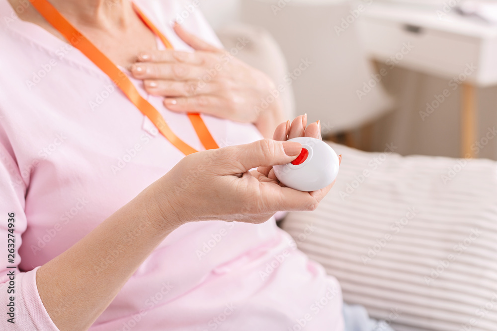 Senior woman feeling heart pain and pressing emergency call button