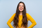 Teenager girl over isolated blue wall laughing