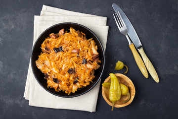 Wall Mural - Traditional dish of polish cuisine - Bigos from fresh cabbage, meat and prunes. Top view. Dark background.