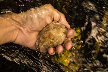 Person holding a stone in the water of a waterfall