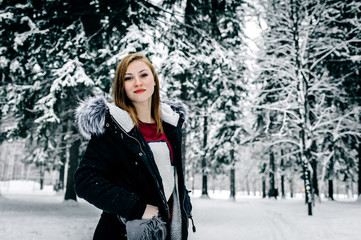 Wall Mural - Portrait of a girl in the black jacket with fur hood amid winter forest