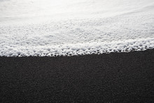 Foam Left By A Breaking Wave On A Black Beach In Iceland