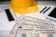 © Miljan Živković - Construction industry costs money us dollars banknotes by tools safety equipment and blueprints
