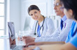 © lenets_tan - Smiling doctor using a laptop working with her colleagues in a bright hospital room