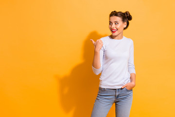 Poster - Portrait of cute isolated charming student impressed by choice decision. She is pointing at copyspace by her thumb dressed in white jumper blue denim clothing over vibrant background