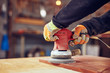 © astrosystem - Male carpenter using orbital electric sander in a retro vintage workshop.