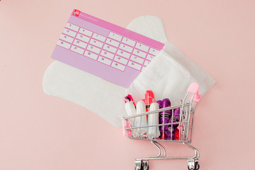 Tampon, feminine, sanitary pads for critical days, feminine calendar, pain pills during menstruation on a pink background. Tracking the menstrual cycle and ovulation