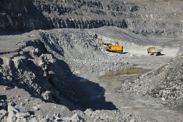 Excavator and mining truck at the bottom of the quarry, top view.