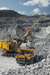 © esalienko - Heavy mining excavator loads rock ore into a dump-body large mining truck. Quarry equipment. Mining industry.