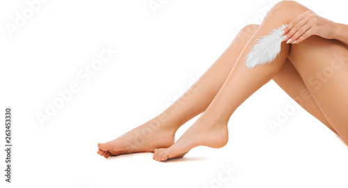 Photographie woman touching with feather to her shiny smooth skin on legs after hair removed
