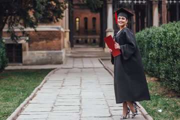 Wall Mural - Happy to be graduated. Happy young woman in graduation gowns holding diploma!