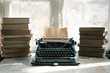 Typewriter and stack of books on a writer table background.