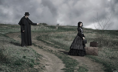 Outdoors portrait of a victorian lady in black and gentleman talking to her from the oppisite sides of the road.