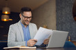 © Goran - Happy businessman working on reports in the office