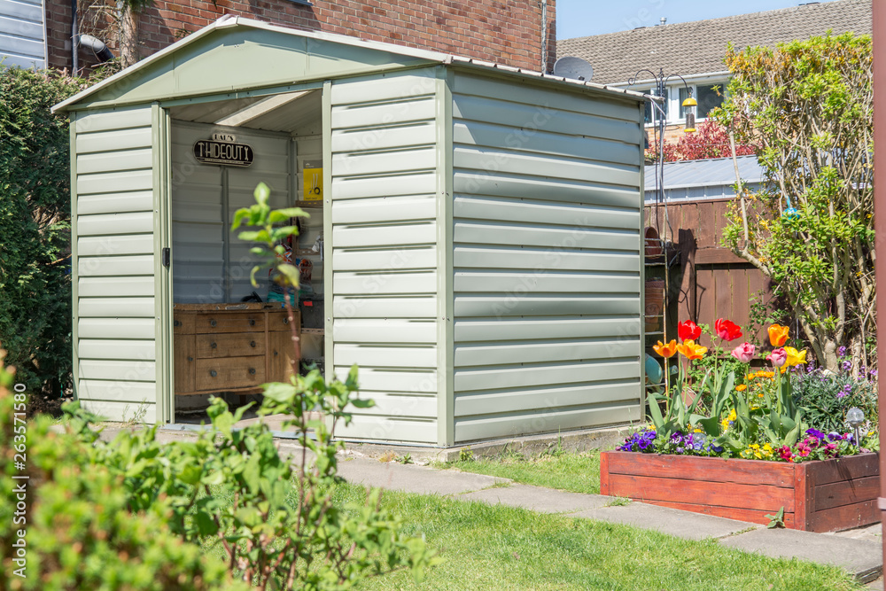 A modern shed and breautiful grden with blooming flowers and a Dads hideout sign in the shed. - obrazy, fototapety, plakaty 
