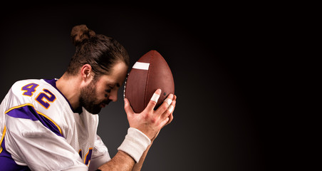 american football player with a ball On moment to pray before the game