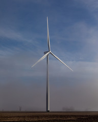 windmill rising above low hanging fog on a sunny morning in the countryside