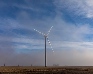 windmill rising above low hanging fog on a sunny morning in the countryside