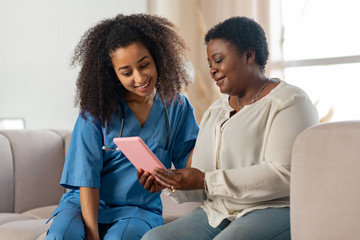 patient and nurse sitting on sofa while watching movie on tablet