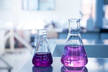 Wall Mural - purple water solution in two size of glass flask in chemical blue science laboratory background