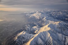 Aerial View From Airplane Of The Wasatch Front Rocky Mountain Range With Snow Capped Peaks In Winter Including Urban Cities Of Provo, Farmington Bountiful, Orem And Salt Lake City. Utah. United States