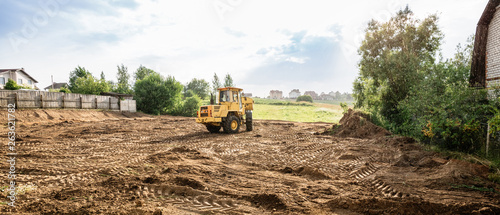 Cuadros en Lienzo large yellow wheel loader aligns a piece of land for a new building, wih copy sp