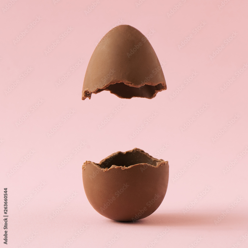Chocolate Easter egg broken in half on pastel pink background with ...