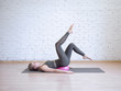 © junky_jess - Beautiful young woman doing pilates workout with small pink fitness ball, leg arch exercise. Indoor, loft background, toned blue.