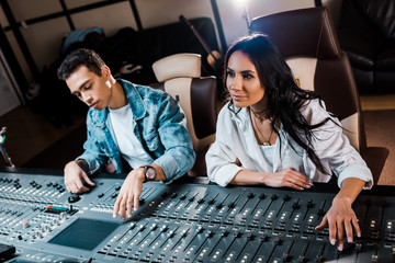 Canvas Print - two young attentive multicultural sound producers working at mixing console in recording studio