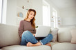 © deagreez - Portrait of her she nice-looking attractive lovely serious wavy-haired girl sitting on divan lotus position chatting online net web site in light white interior room