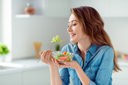 Close-up portrait of her she nice-looking sweet lovely charming cute attractive cheerful cheery positive brown-haired lady tasting new salad mix farm vegs in light white interior style kitchen