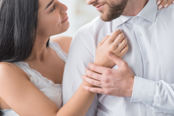 cropped view of young woman hugging cheerful boyfriend in white shirt