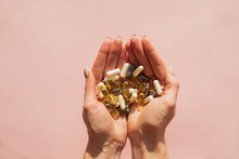 Woman's hands holding a lot of different pills or dietic supplements