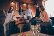 © deagreez - Close up photo serenade gathering best friends hang out vocal soloist play guitar fiance bride surprise romantic she her ladies he him his guys wear dress shirts formal wear sit sofa loft room indoors