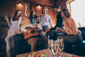 Close up photo serenade gathering best friends hang out vocal soloist play guitar fiance bride surprise romantic she her ladies he him his guys wear dress shirts formal wear sit sofa loft room indoors